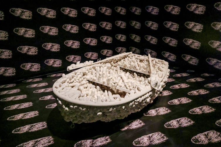 A boat with white blobby figures growing out of it.
